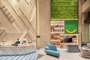 A modern lobby with a reception desk, seating area, and a green wall feature. - Holiday Inn Shanghai Nanjing Road by IHG (Shanghai)
