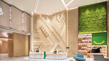 A modern lobby with a reception desk, seating area, and a green vertical garden wall.