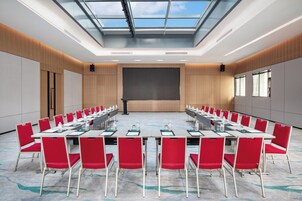 Una sala conferenze con soffitto alto, lucernari e un grande schermo.