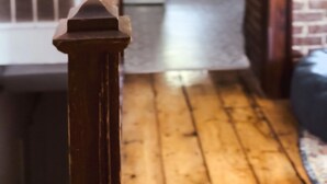 A wooden staircase leading to a kitchen area with a brick wall and a window. - The Attic: 2br - 1bth - 4 guests (Champaign)