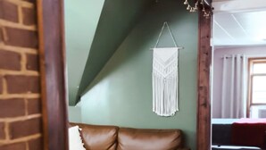 A cozy living room with a brown leather sofa, a round rug, and a macrame wall hanging. - The Attic: 2br - 1bth - 4 guests (Champaign)
