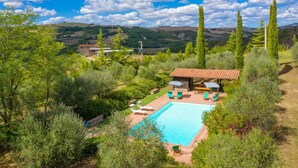 A pool area with lounge chairs and a covered seating area, surrounded by greenery and hills in the background. - Villa Il Giulione Large Private Pool, WiFi (Acquapendente)