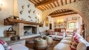 A rustic living room with a stone fireplace, wooden beams, and a stone archway. - Villa Il Giulione Large Private Pool, WiFi (Acquapendente)