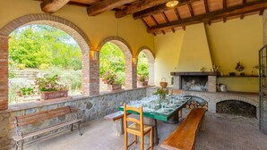 An outdoor dining area with a brick fireplace, stone arches, and a bench. - Villa Il Giulione Large Private Pool, WiFi (Acquapendente)