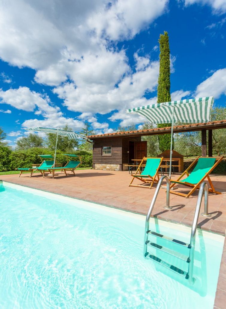 Un espace piscine avec des chaises longues et un petit bâtiment doté d’un toit en tuiles.