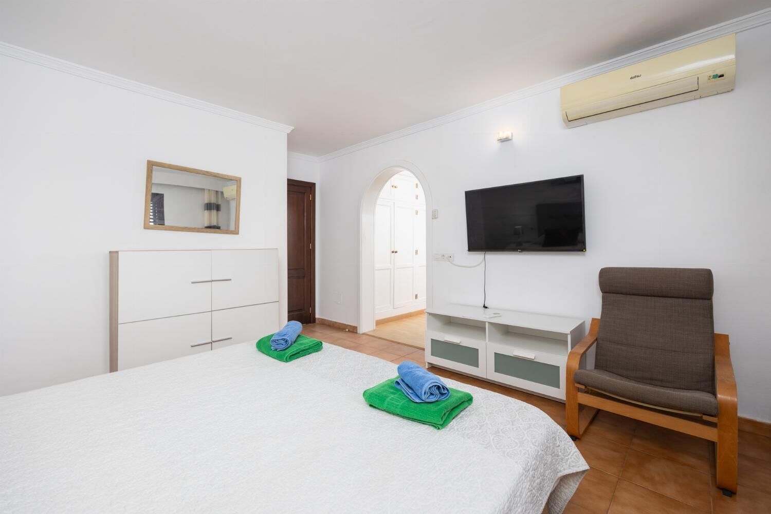 Ett hotellrum med en säng, en tv, en stol och en luftkonditioneringsanläggning.