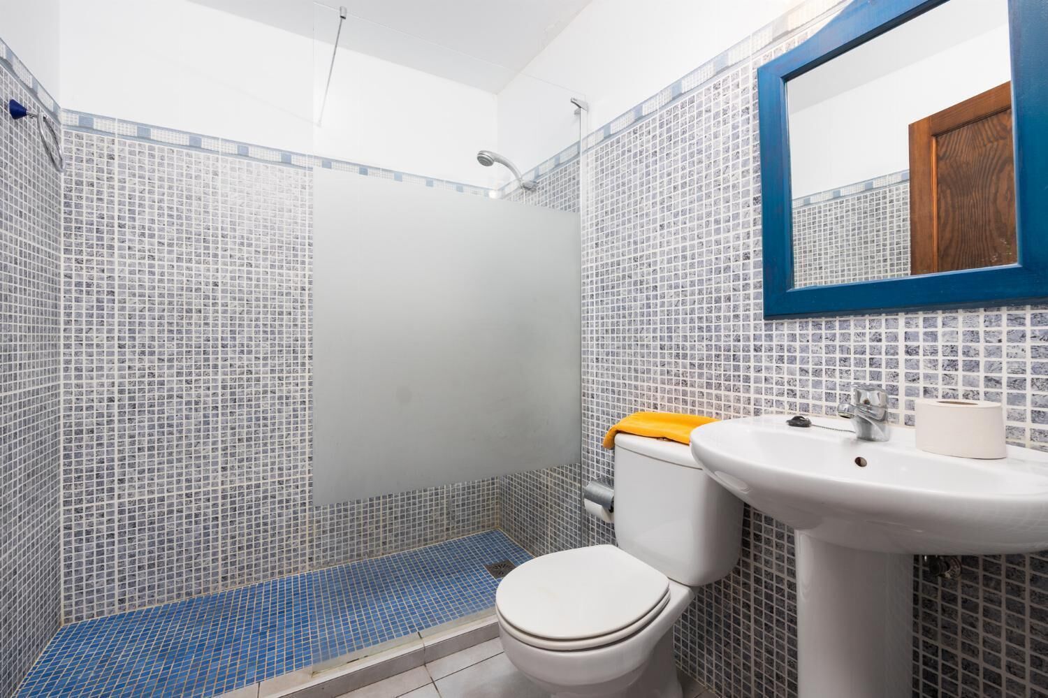 A bathroom with a tiled shower, a toilet, and a sink.