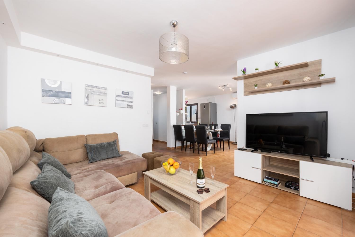 Un salon moderne avec un canapé, un téléviseur et un coin repas à l’arrière-plan.