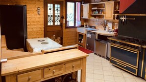 Une cuisine de taille réduite avec des murs en bois, une table à manger, un réfrigérateur, une cuisinière et un évier.
