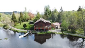 Un chalet avec une façade en bois, un quai et un étang.