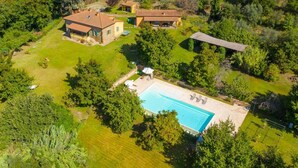 Vista aérea de una propiedad con piscina, varios edificios y abundante vegetación.