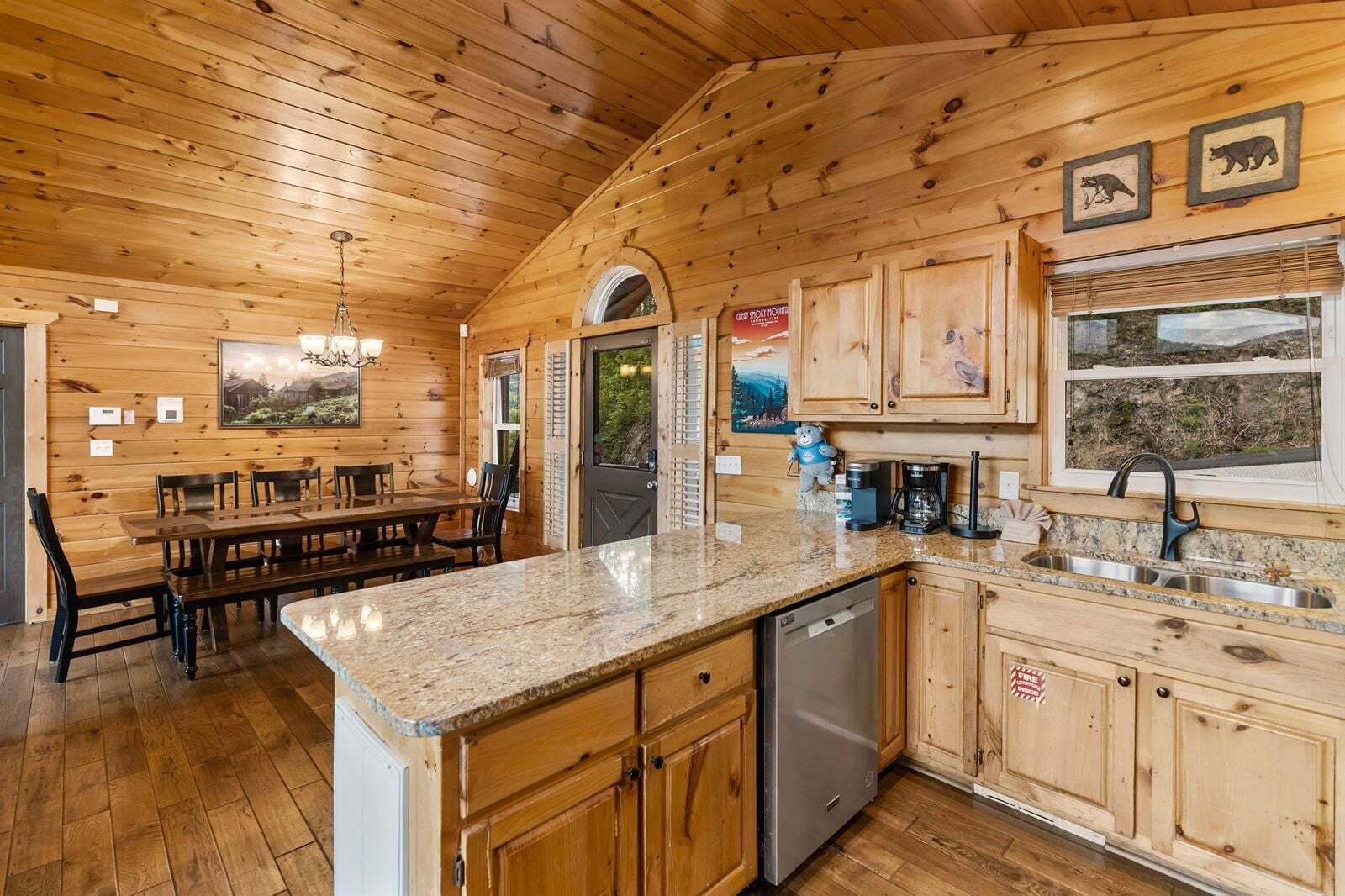 A wooden interior with a dining area, kitchen, and a view through a window.