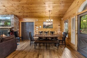 Interior de madera con chimenea, mesa de comedor y sillas.