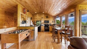 Interior de madera con cocina, zona de comedor y vistas al exterior.
