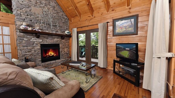 A cozy living room with a stone fireplace, a television, and a comfortable seating area.