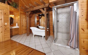 A wooden cabin bathroom with a freestanding bathtub, a shower, and a sink with a mirror.