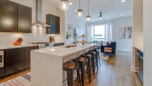 Une cuisine moderne dotée d’un îlot central, de tabourets de bar et de luminaires suspendus.