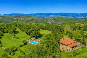A villa with a swimming pool surrounded by lush greenery and hills in the background. - Villa Bellavista Large Private Pool, WiFi (Ortignano Raggiolo)