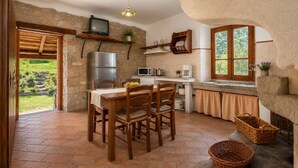 A rustic kitchen with a stone wall, wooden furniture, and a television. - Villa Bellavista Large Private Pool, WiFi (Ortignano Raggiolo)