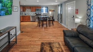 A modern living room with a wooden floor, a black leather sofa, and a dining area with a table and chairs. - Cozy and Budget Friendly Single Bedroom in Denver (Denver)