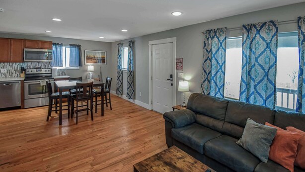 A modern living room with a dark leather sofa, wooden coffee table, and a dining area with a table and chairs. - Cozy and Budget Friendly Single Bedroom in Denver (Denver)