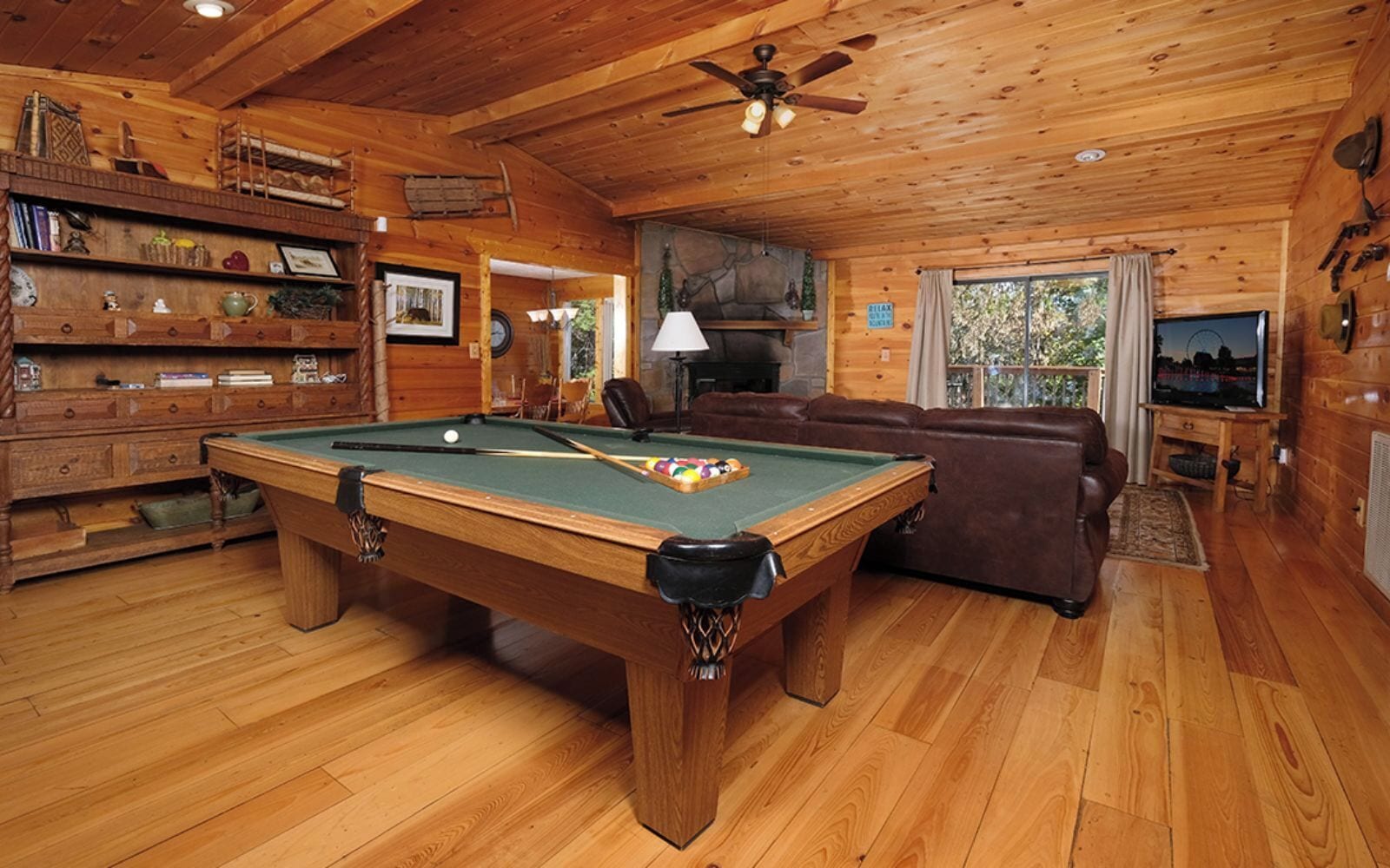 Een houten interieur met een pooltafel, een leren bank en een open haard.