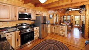 A spacious kitchen with wooden cabinets, stainless steel appliances, and a large island. - Paradise in the Treetops, Hot Tub, Game Loft & Fireplace - Almost Bearadise (Sevierville)