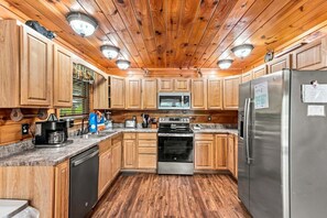 A kitchen with wooden cabinets, a stainless steel refrigerator, a microwave, and a stove.