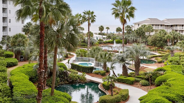 Un complexe hôtelier doté de plusieurs piscines, de palmiers et de jardins bien entretenus.