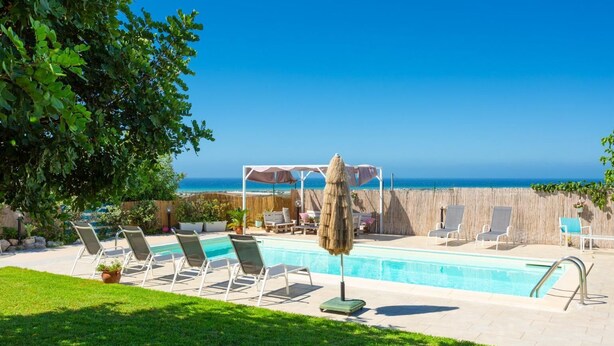 Ein Poolbereich mit Liegestühlen, einer Pergola und Meerblick.
