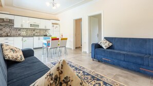 Un salon moderne avec un canapé bleu, un tapis à motifs et un coin repas agrémenté de chaises colorées.