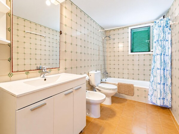 A bathroom with a white sink, two toilets, a bathtub, and a shower.