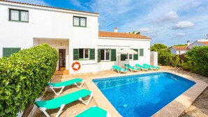 Une villa blanche avec une piscine, des volets verts et une bouée de sauvetage.