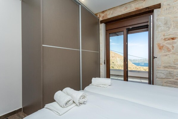 A bedroom with a bed, a large sliding door, and a view of a coastal landscape.