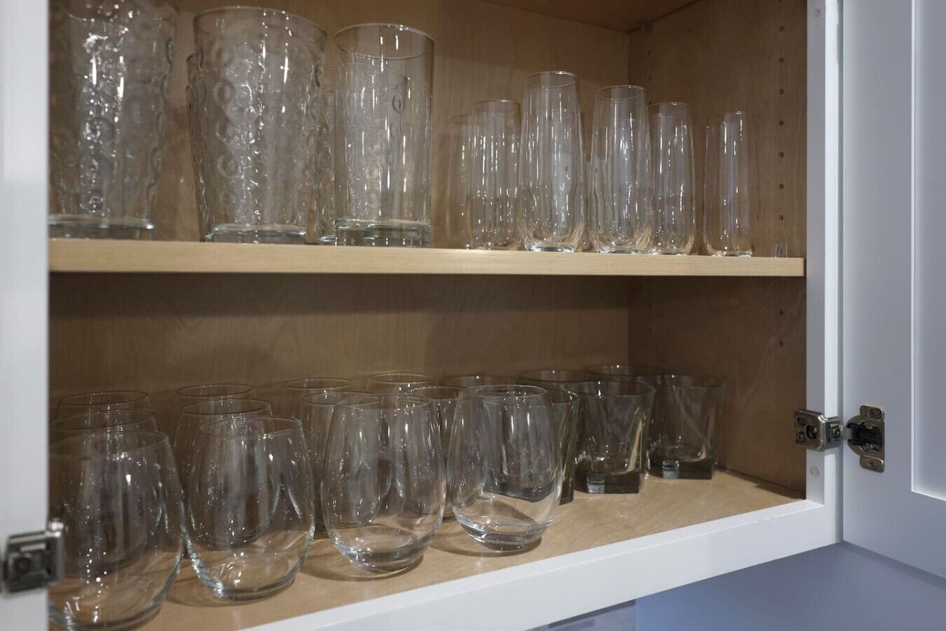 A cabinet with two shelves of clear glassware.