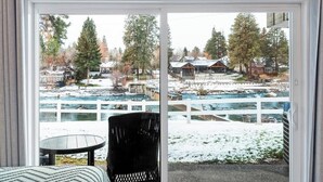Ein Zimmer mit einem großen Schiebeglastür, die zu einer verschneiten Außenanlage mit Fluss und Häusern führt.