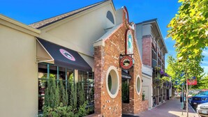 Ein Backsteinhaus mit einer Beschilderung für Deschutes Brewery, ein Laden mit einer schwarzen Markise und ein Bürgersteig mit Baum und parkenden Autos.