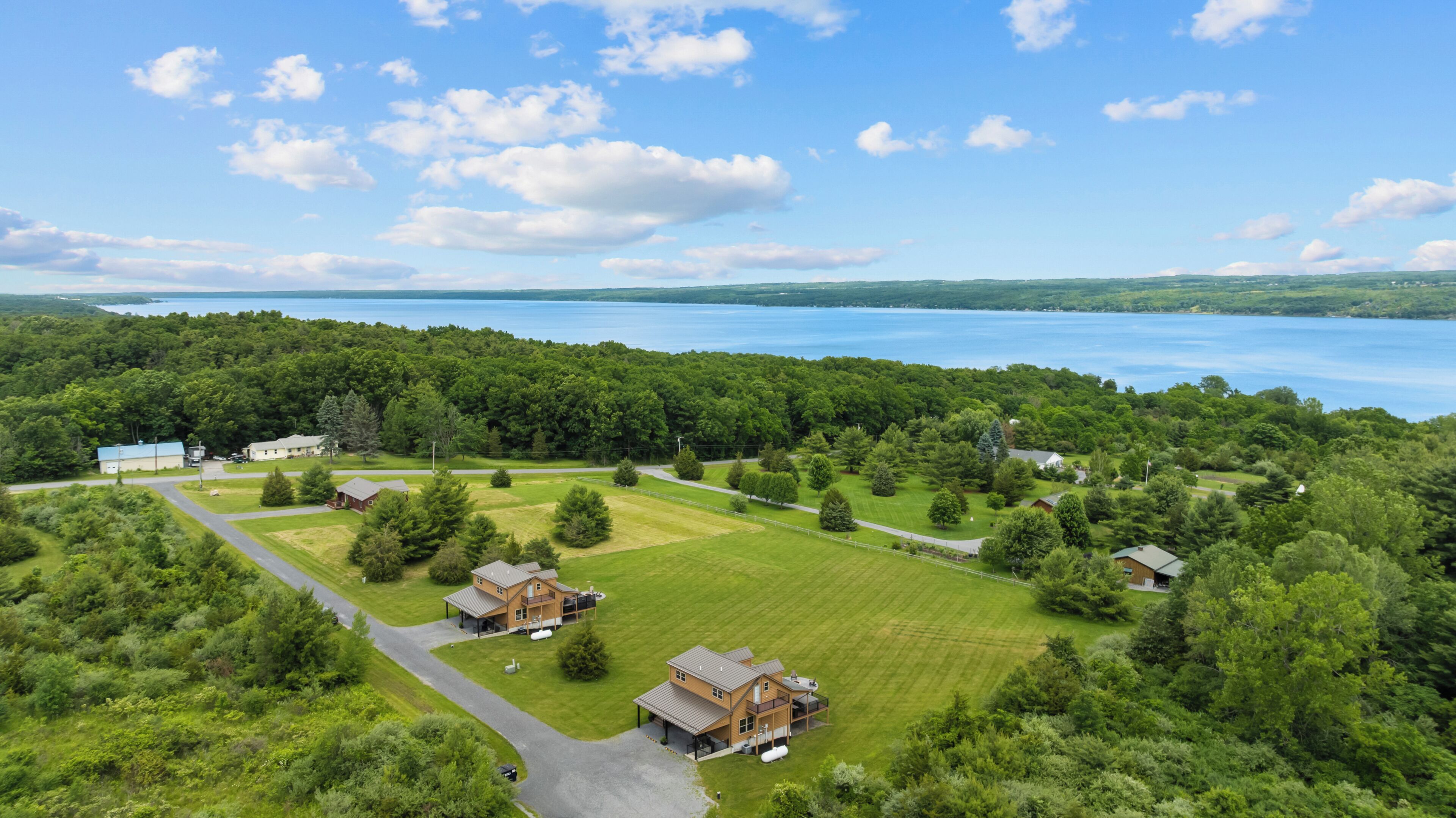 A large property with multiple buildings, a well-maintained lawn, and a lake in the background.