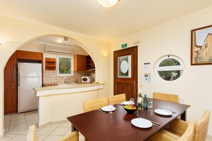 Un coin repas avec une table en bois, des chaises et une vue sur la cuisine.