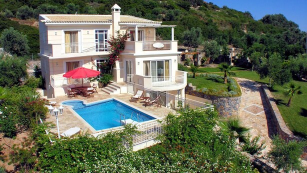 Eine zweistöckige Villa mit Swimmingpool, Sitzgelegenheiten im Freien und einem üppigen Garten.