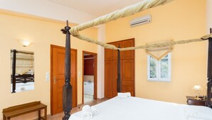 Ein Hotelzimmer mit Himmelbett, Holzschrank und einer Bank.