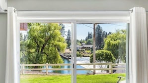 Habitación con un amplio ventanal corredero que da a una vista de un río, árboles y un puente.