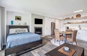 Une chambre à coucher comprenant un lit, une télévision, une cheminée et un coin repas avec des chaises et une table.