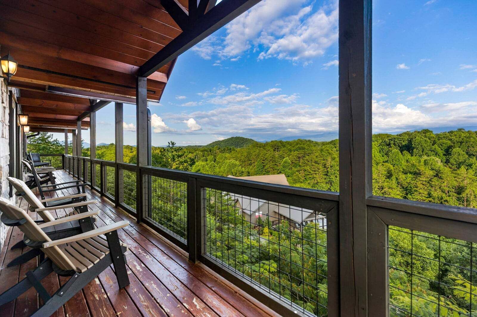 Un espacio al aire libre techado con piso de madera, barandillas metálicas y sillas.