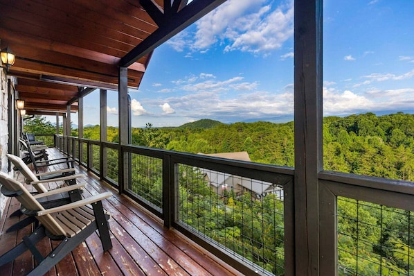 A covered outdoor area with wooden flooring, metal railings, and chairs. - Splash Mansion - Indoor Pool and Theater (Sevierville)