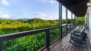 A wooden deck with a railing overlooking a forested hillside. - Splash Mansion - Indoor Pool and Theater (Sevierville)