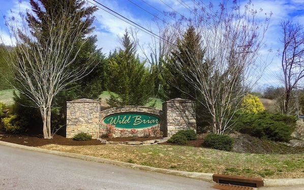A sign for Wild Briar with stone walls and trees.