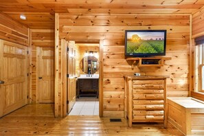 A wooden interior with a television mounted on the wall, a sink, and a mirror. - Splash Mansion - Indoor Pool and Theater (Sevierville)