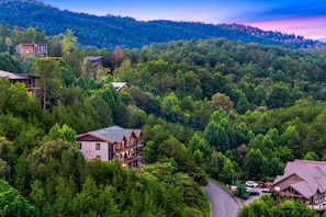 A mountainous area with a road leading to a building with a red roof and a balcony. - Splash Mansion - Indoor Pool and Theater (Sevierville)