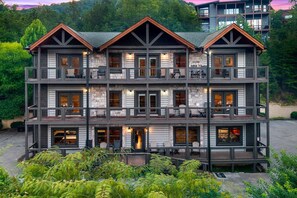 Un chalet à plusieurs étages doté de balcons, de grandes fenêtres et d’une façade en pierre.